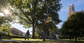 Person walking up to the Cathedral of learning at University of Pittsburgh